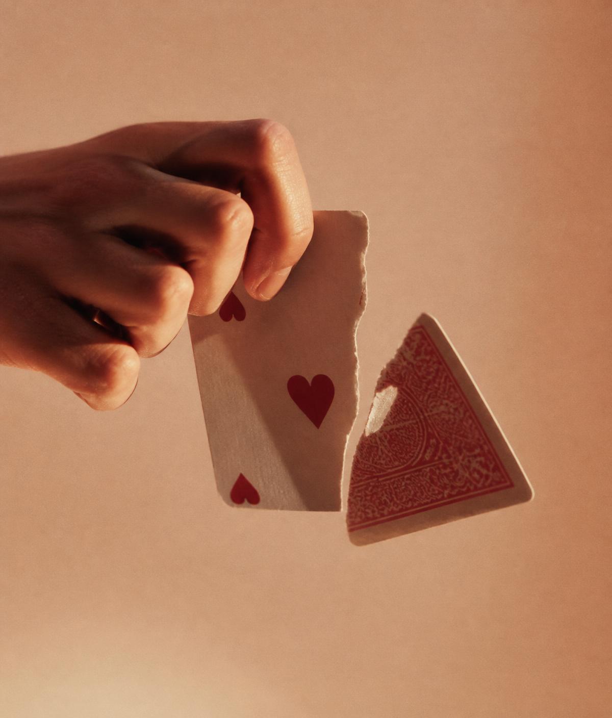 A hand tearing a playing card in half
